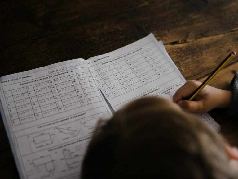 Matematik alıştırma kâğıdında çarpma ve çevre soruları çözen öğrenci